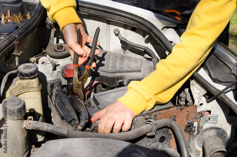 Asian female mechanic dressed in special clothes fixing a car near the house