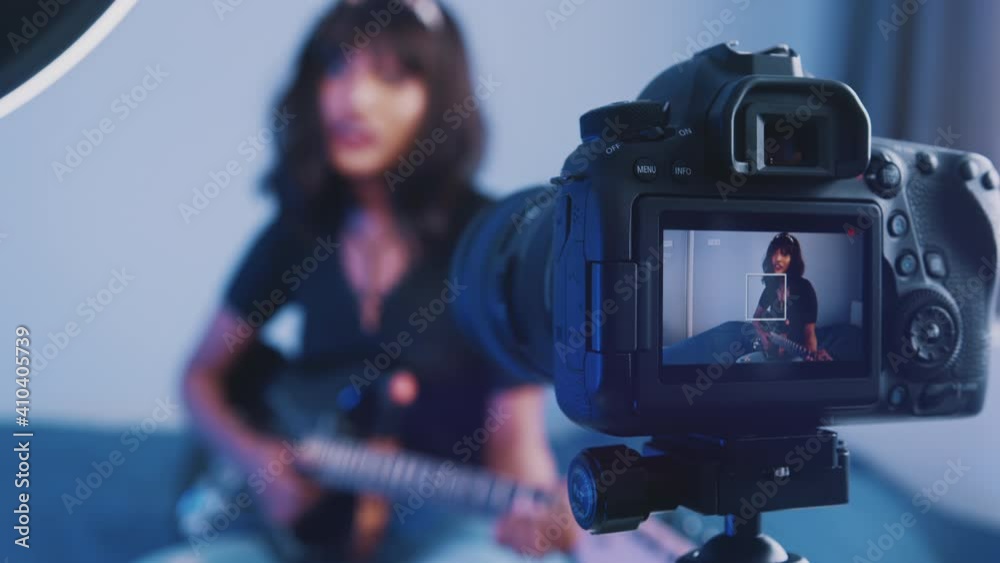 Young woman playing guitar in front of the camera. recording demo or giving online class. High quality 4k footage