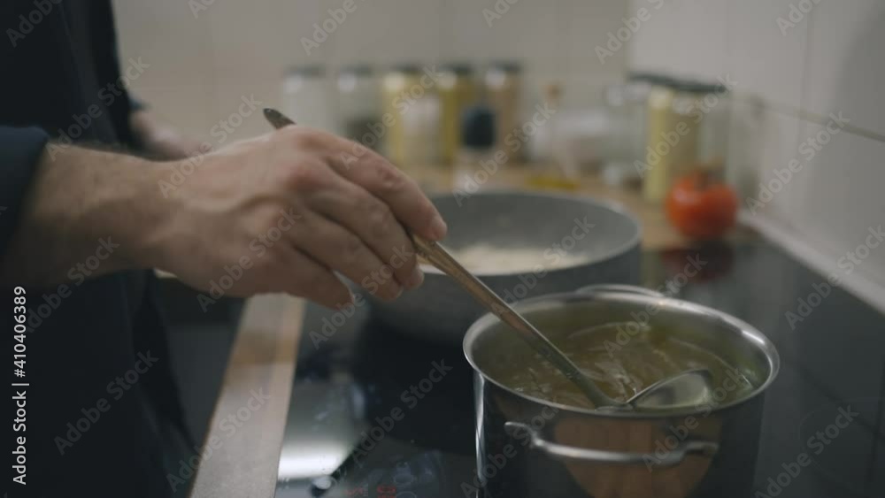 Chef pouring chicken stock in risotto