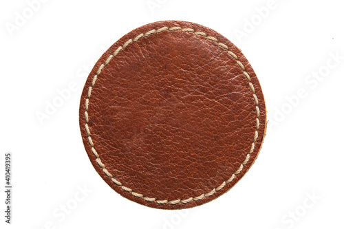 Blank brown round leather label on white background, macro close up. Empty leatherette circular tag