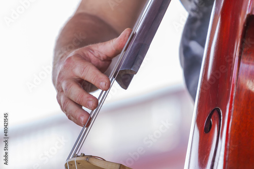 Detalhe de mão de músico tocando baixo acústico