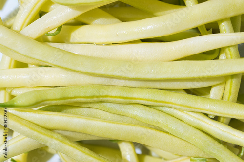 Yellow raw wax beans texture close up, long ripe pods full frame food background