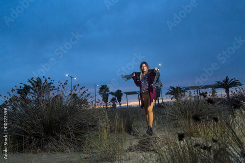 Bella ragazza mora, con maglione color amaranto e sciarpa al collo passeggia vicino alla riva del mare
