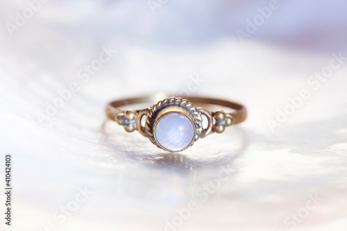 Brass ring with moon stone mineral stone on white shell background