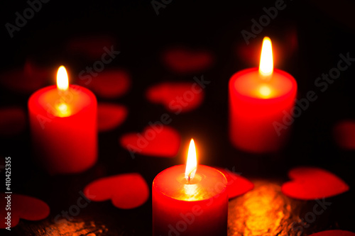 Three red burning candles. Candles with hearts. The background for the greeting card. A greeting card for Valentine s Day. February 14 is valentine s day. Used as a background or texture  soft focus