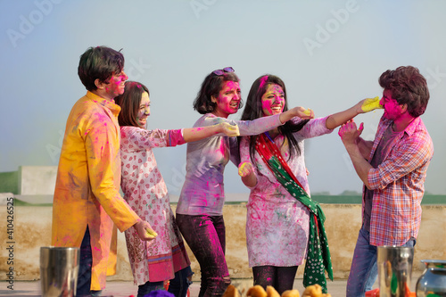 A GROUP OF YOUNG MEN AND WOMEN CELEBRATING HOLI TOGETHER 
