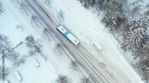 The city bus is moving on the street in winter.