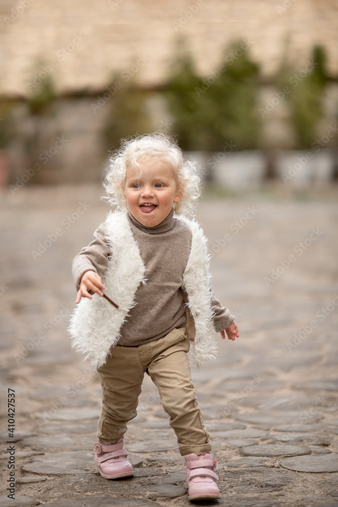 Curly toddler with blond hair having fun on a walk on a summer day Curly toddler with blond hair having fun on a walk on a summer day