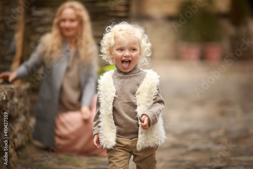 Curly toddler with blond hair having fun and laughing on a walk with her mom