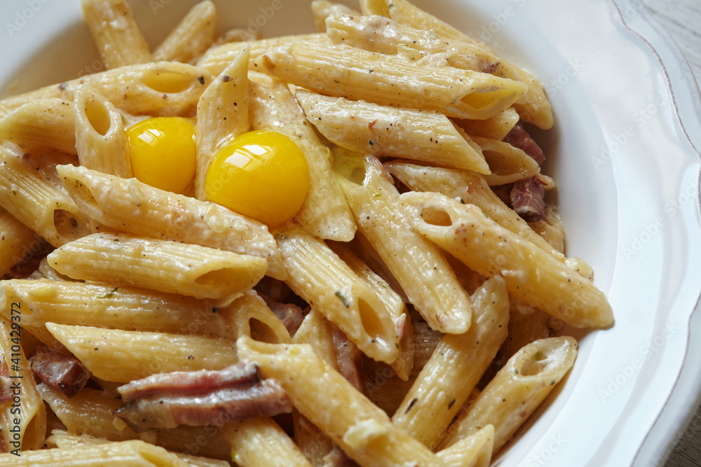Spaghetti Carbonara, pasta with bacon, egg, hard parmesan cheese and cream sauce. Traditional italian Pasta alla carbonara on white, top view, copy space.