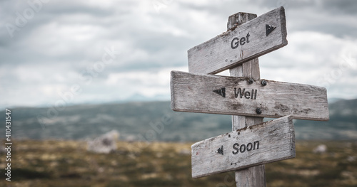 get well soon text engraved on wooden signpost outdoors in nature. Panorama format.