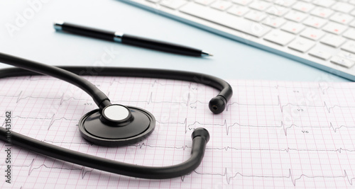 Stethoscope on cardiogram with pen and keyboard on blue background. Cardiology concept. Panoramic web banner.