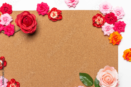 Frame made of rose flowers on cork board background. Top view with copy space.