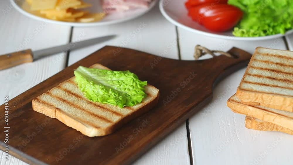 The process of making a sandwich with salad, tomato, ham and cheese. American cuisine. Fast food. Cooking. The process of making a sandwich with salad, tomato, ham and cheese. American cuisine. Fast food. Cooking.