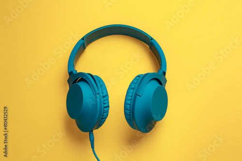 Trendy blue headphone on yellow background. Music concept.