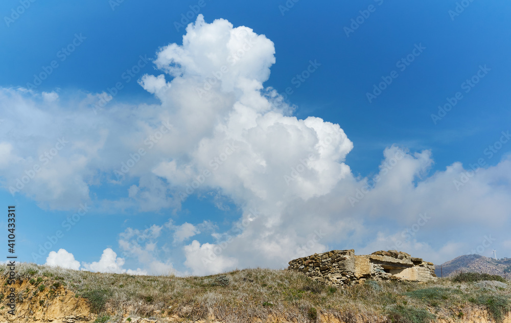Ruins of a military bunker on Tarifa coastline against a blue sky with cumulonimbus cloud