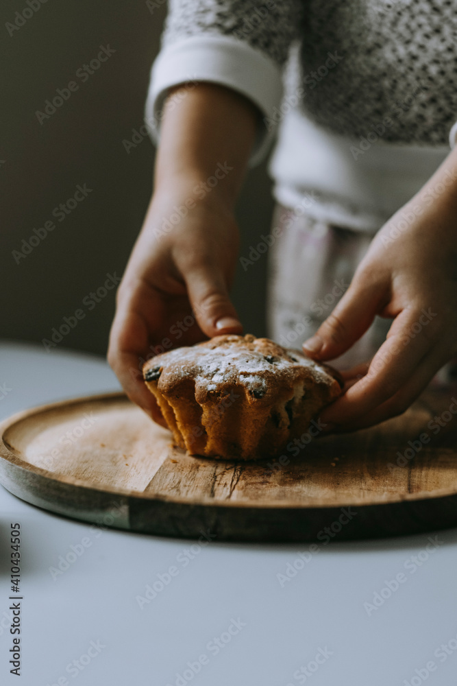 children's hands reach for a cupcake on a wooden platter