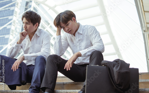 Two unemployed workers sitting beside the street and being sad