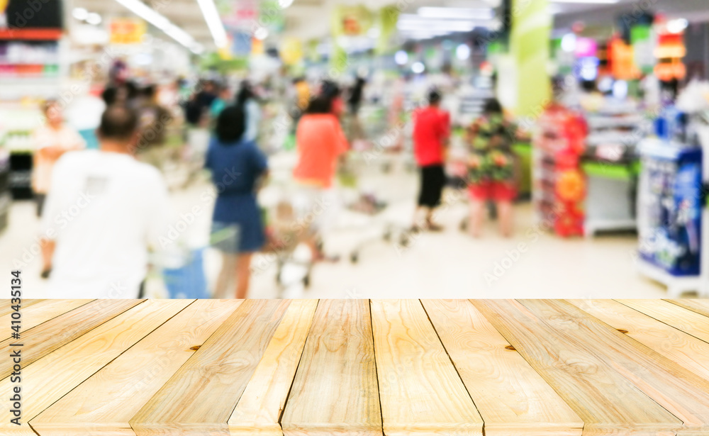 Wooden board empty table on front with blurry many crowd anomynous waiting for payment at cashier.