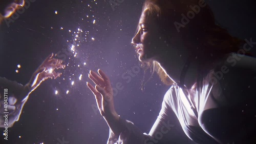 magic underwater shot of young woman floating in depth and looking on her reflection in water mirror