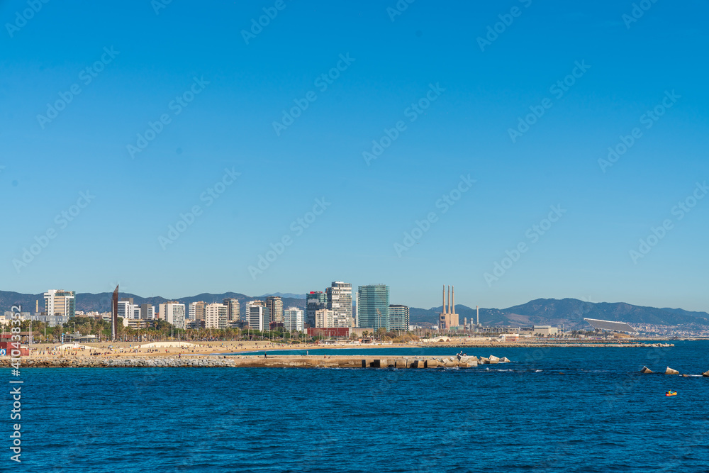BARCELONA, SPAIN, FEBRUARY 3, 2021: Barcelona coast a sunny winter day. During the covid-19 pandemic. View from inside the water. In the background we can see the new modernist buildings on the coast.