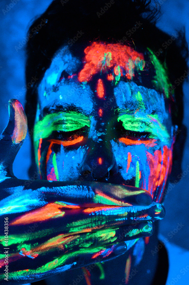 Hombre con pinturas glow in the dark, pintado de colores brillantes y artístico