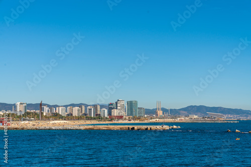 BARCELONA, SPAIN, FEBRUARY 3, 2021: Barcelona coast a sunny winter day. During the covid-19 pandemic. View from inside the water. In the background we can see the new modernist buildings on the coast.