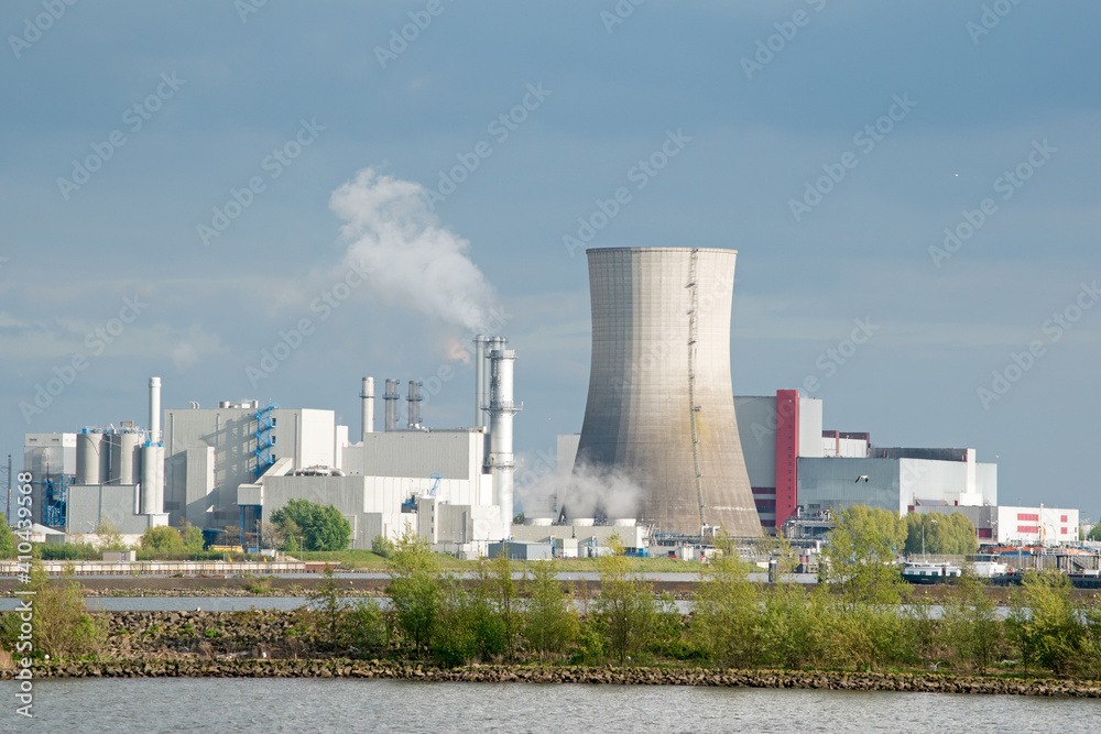 Steam rises from a chimney at a power station along the river in The Netherlands.