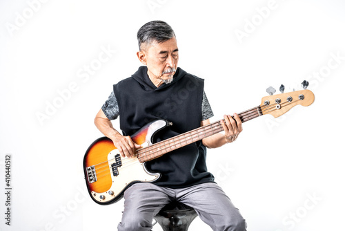 An Asian elder cool man has fashion in gray t-shirt And black vest play bass guitar. Shoot On white background in the studio. Positive active old cool senior healthy retirement concept