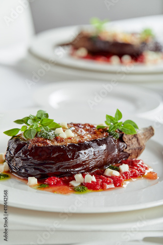 Half baked eggplants with meat, cheese and tomatoes on white background. Banquet festive dishes. Gourmet restaurant menu. White background.