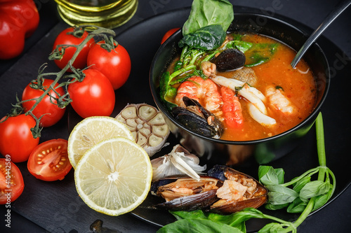 Soup with seafood and vegetables. Still life on a dark background. photo