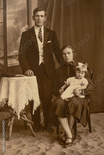 Germany - CIRCA 1930s: A family studio shot of married couple with a child in studio. Vintage art deco era photo