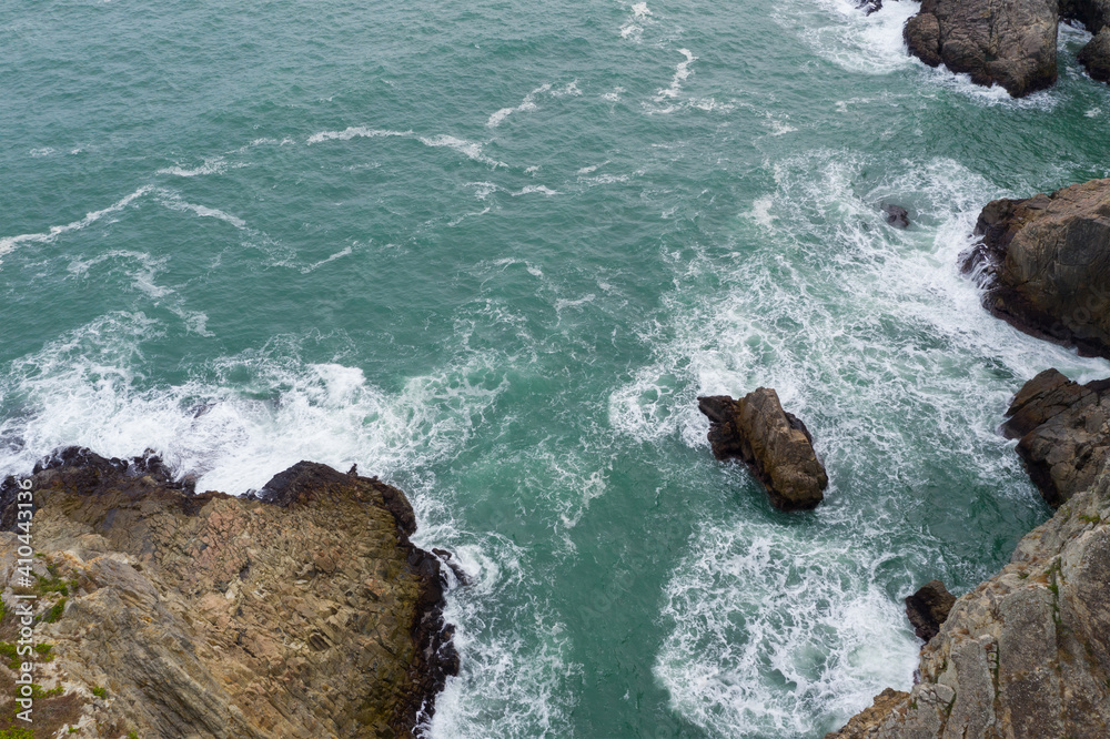 Top down view of sea water waves break on rocks