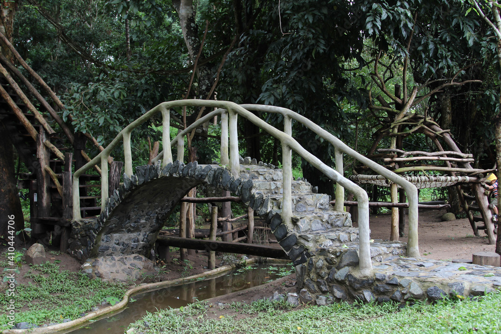 A stone bridge in the park across small stream. A stone bridge in the park across small stream.