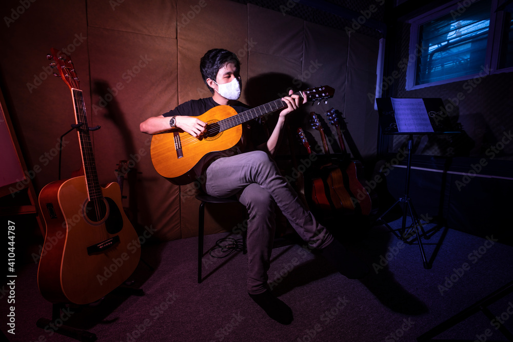 Fototapeta Beautiful young asian man play on guitar. Boy sitting in studio music recording room with acoustic guitar.