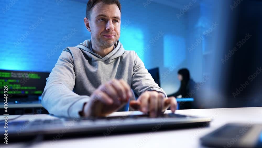 Middle shot of nervous programmer typing on computer keyboard in blue office. Portrait of concentrated Caucasian stressed man coding or hacking indoors. Programming concept. Middle shot of nervous programmer typing on computer keyboard in blue office. Portrait of concentrated Caucasian stressed man coding or hacking indoors. Programming concept.