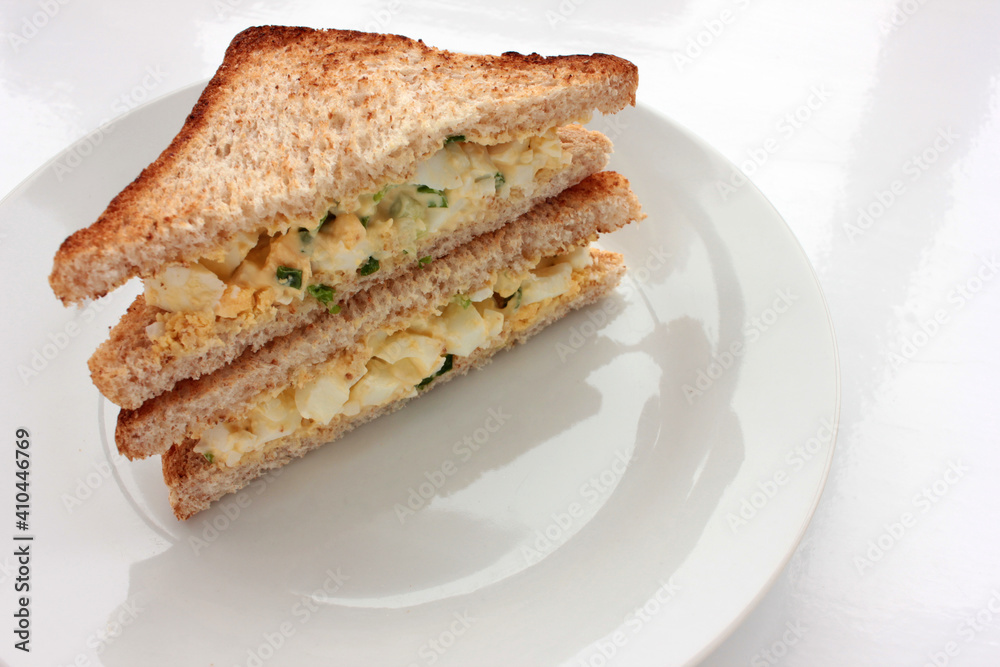 Egg salad sandwich with whole wheat toasted bread on plate on white background. Healthy snack concept