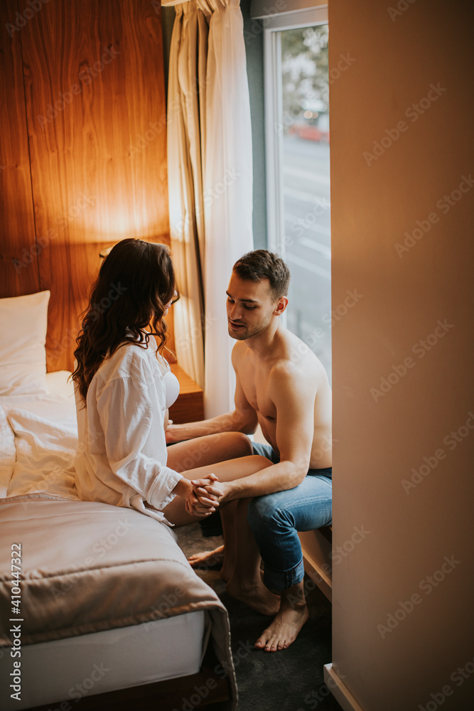 Lovely couple hugging on their bed at home by the window Lovely couple hugging on their bed at home by the window