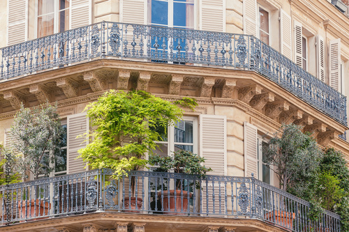 Beautiful Haussmannian building facade in Paris with balcony decorated with plants