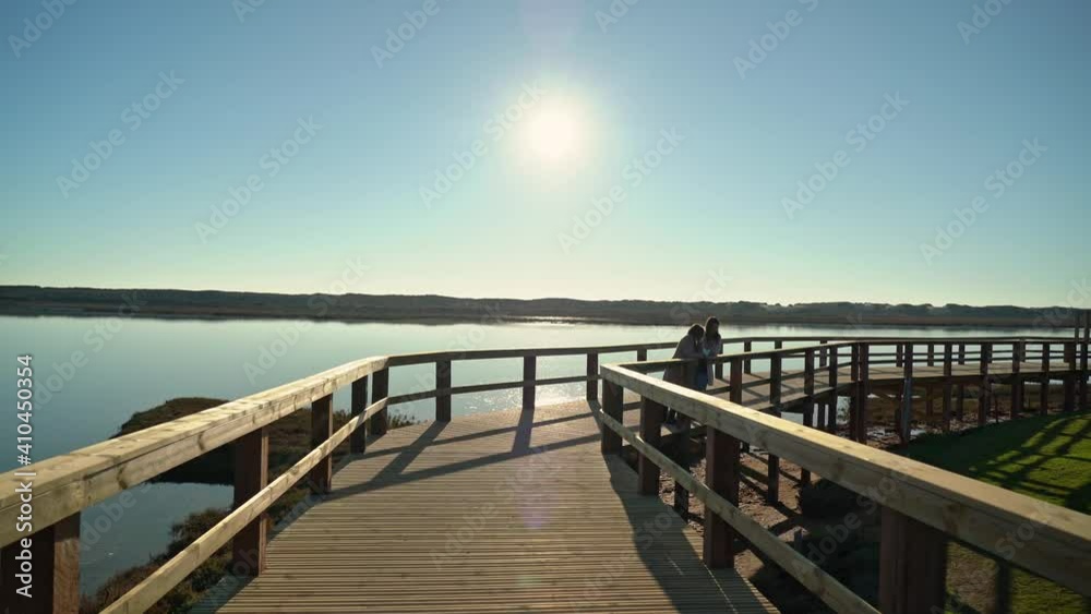 Two females communicate on a boardwalk near a river shore. Sao Lourenco Quinta de Lago, Almancil. Portugal Two females communicate on a boardwalk near a river shore. Sao Lourenco Quinta de Lago, Almancil. Portugal