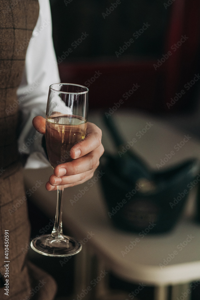 a glass of champagne in the hand of a brutal man