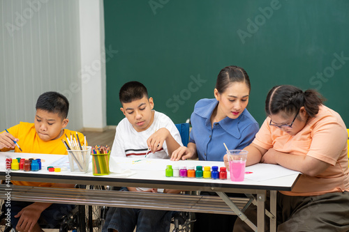 Asian disability boy learning color Painting in classroom with Autism girl in special school with female teacher.