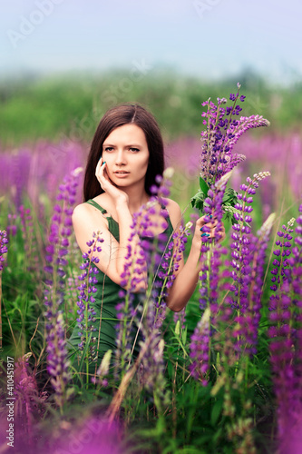 girl in a green dress on a lupine field. summer day