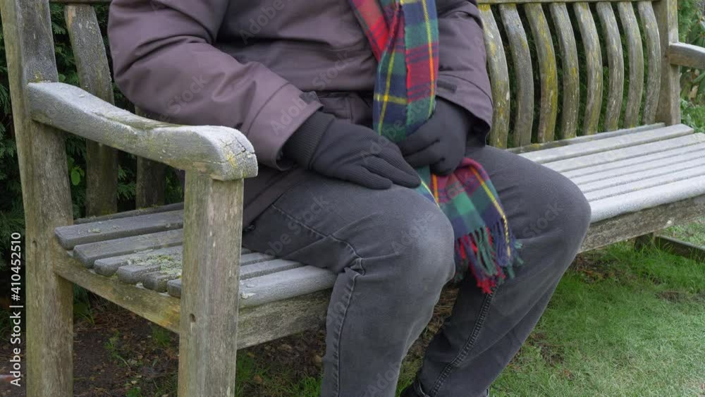 Closeup of an anonymous person in winter clothing sitting on a frosty wooden park bench, then getting up to go and leaving an arm and seat imprint in the frost. Closeup of an anonymous person in winter clothing sitting on a frosty wooden park bench, then getting up to go and leaving an arm and seat imprint in the frost.
