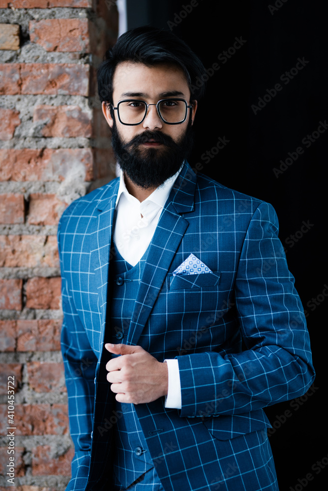 Handsome man in plaid jacket stands near the window and looks at the camera Handsome man in plaid jacket stands near the window and looks at the camera