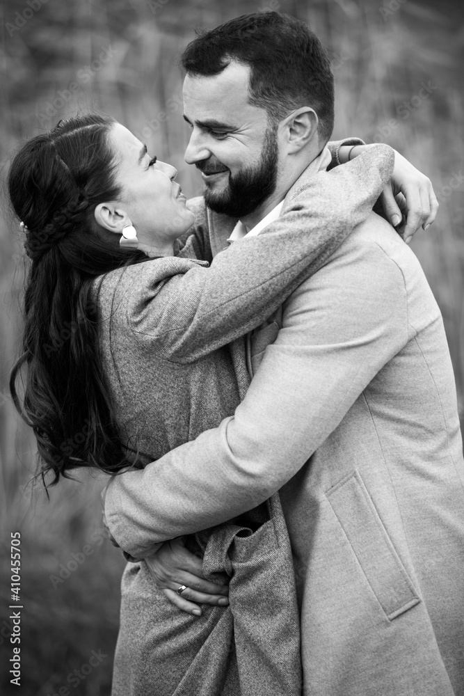 Stylish couple in gray coats gently hugging on the background of reeds. Happy sensual wedding couple embracing. Romantic moments of newlyweds. Stylish couple in gray coats gently hugging on the background of reeds. Happy sensual wedding couple embracing. Romantic moments of newlyweds.
