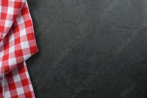 Classic italian cooking background - red checkered tablecloth on a vintage black stone kitchen countertop with copy space