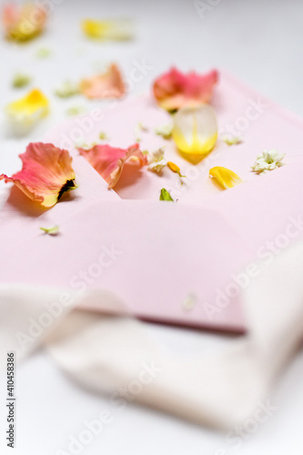 rosa und gelbe Blüten als Detail auf einem rosa Briefumschlag mit weißem Seidenband im Vordergrund | Hochzeitseinaldung, Papeterie,, fine art, romantisch photo