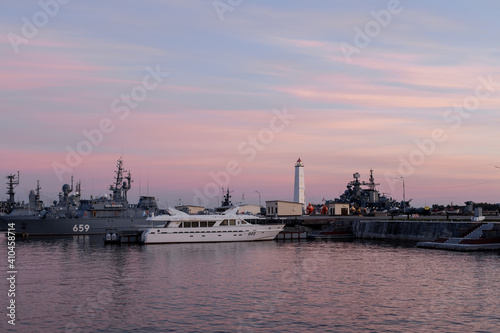 A parade boat for the Russian Navy against the background of a wooden lighthouse in the Petrovskaya pier of Kronstadt. Warships. Russia, Kronstadt, July 20, 2020