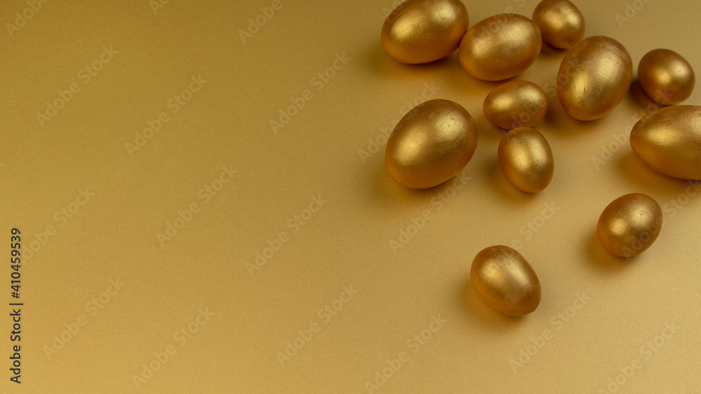 Decorative wooden Easter eggs painted gold on yellow-gold background. Happy Easter greeting card.